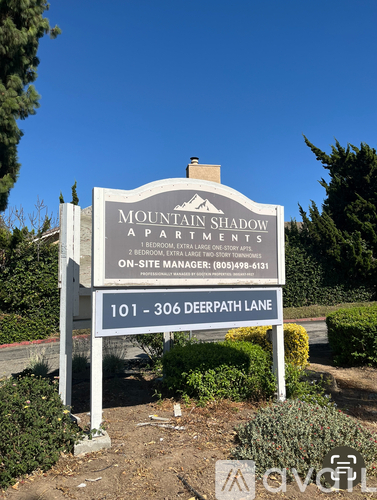 A sign for Mountain Shadow Apartments stands in front of a tree.