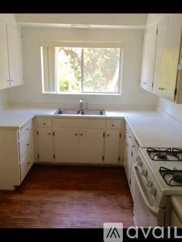 A kitchen with white cabinets and a window.