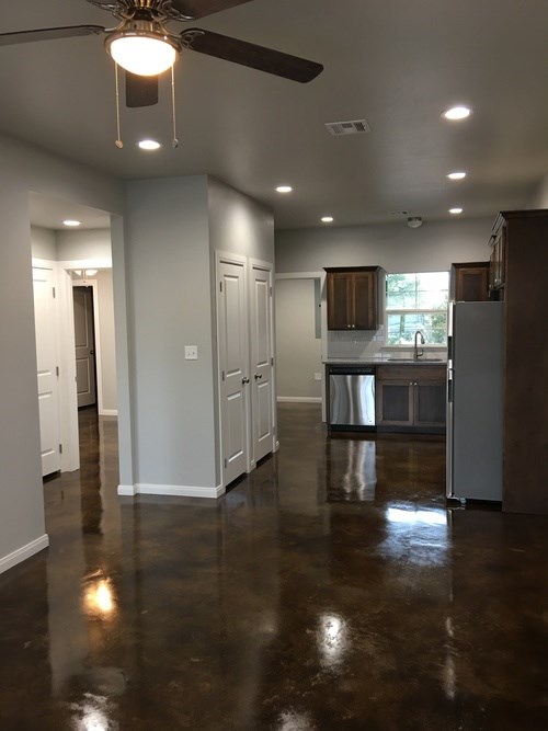 A kitchen with brown floors and a ceiling fan.