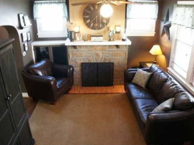 A living room with a fireplace and a clock on the wall.