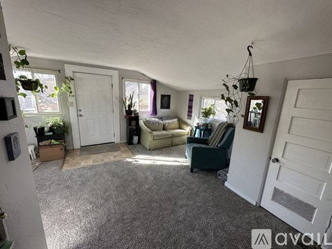 A living room with a grey carpet and a white door.