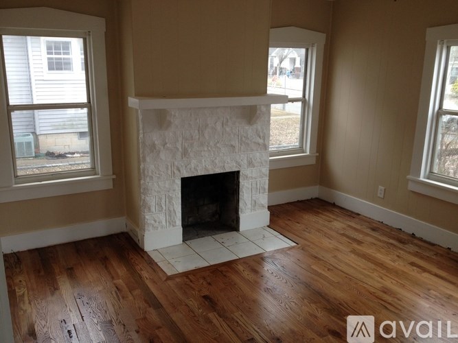 A room with a white fireplace and wooden floors.