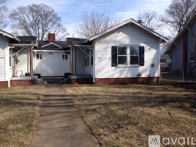 A white house with a black window and a red brick chimney.