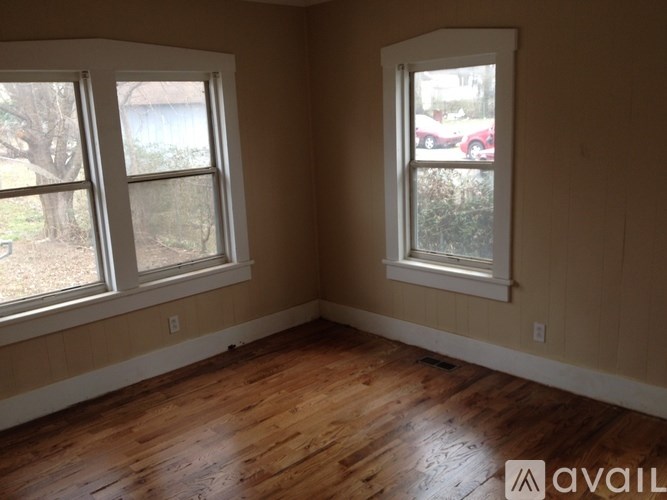 A room with two windows and wooden floors.