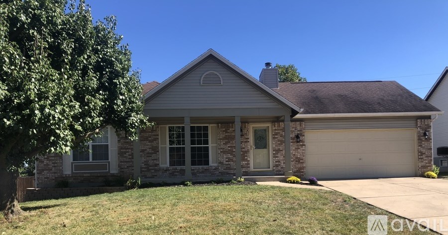 A house with a garage and a tree in front.