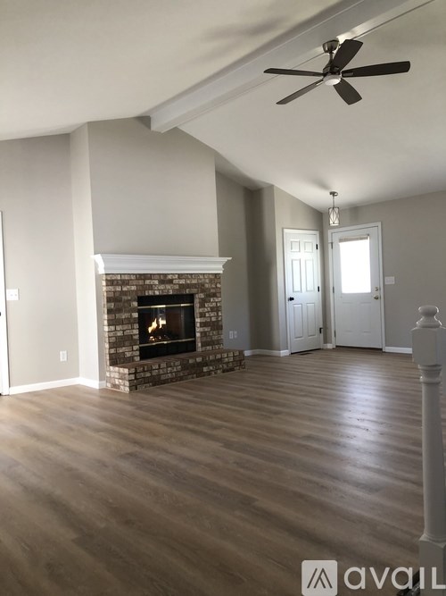 A living room with a fireplace and a ceiling fan.
