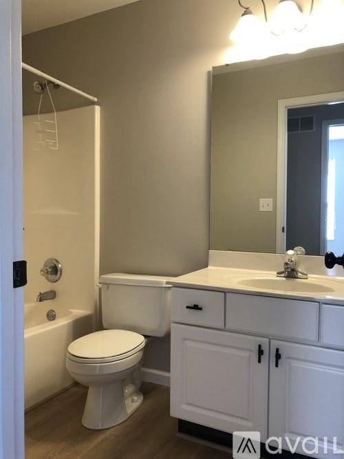 A white toilet is in a bathroom with a white sink and a white cabinet.