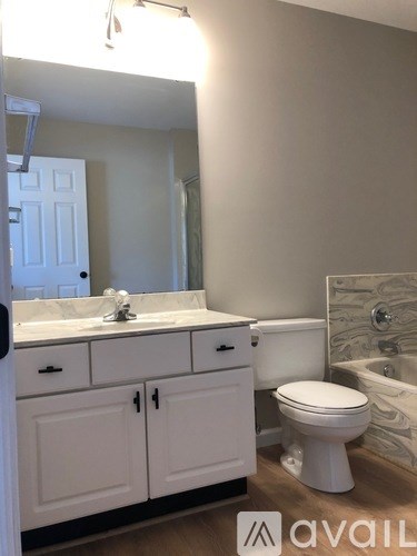 A white bathroom with a toilet, sink, and cabinets.