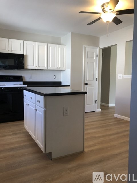 A kitchen with white cabinets and a black countertop.