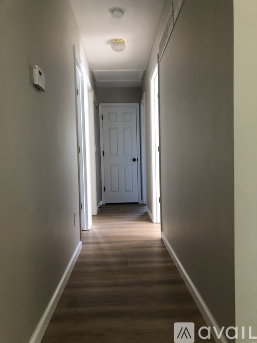 A long hallway with a white door at the end.