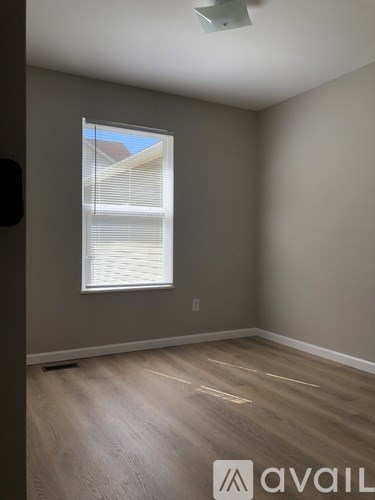 A room with a window and wooden flooring.