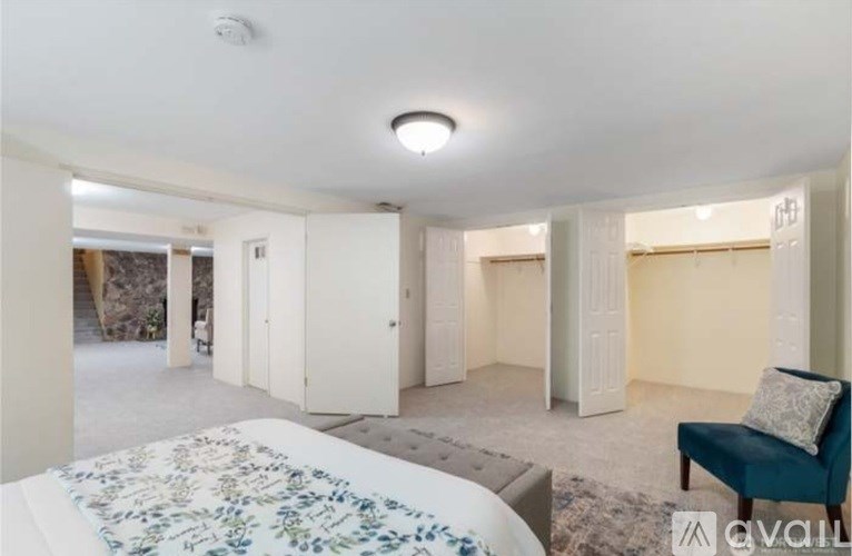 A living room with a floral rug, a blue chair, and a white table.