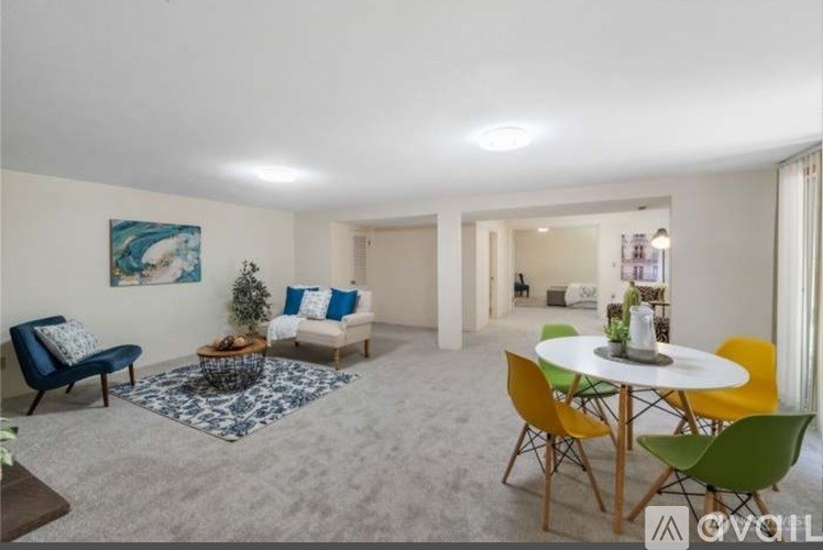 A living room with a blue sofa, a white table, and a painting on the wall.