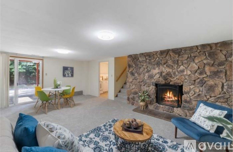 A living room with a stone fireplace and a blue couch.