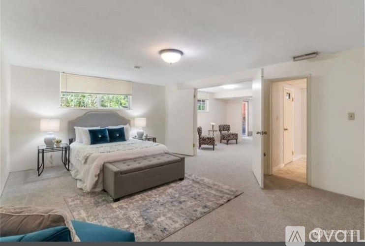 A bedroom with a large bed and a window with blinds.