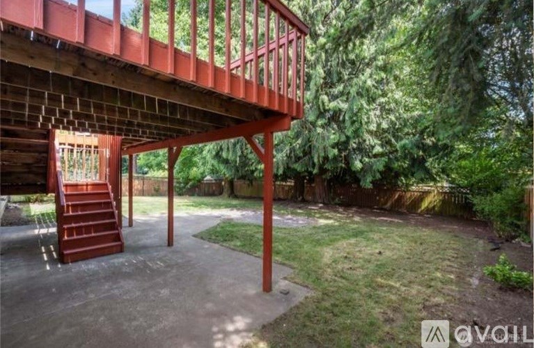 A red wooden deck with a staircase leading to a backyard.