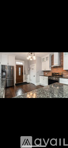 A kitchen with white cabinets and a brick wall.