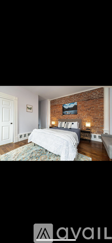A bedroom with a brick wall and a bed.