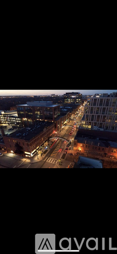 A city street at night with buildings on either side and cars driving.