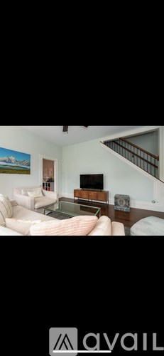 A living room with a couch, coffee table, and a painting on the wall.