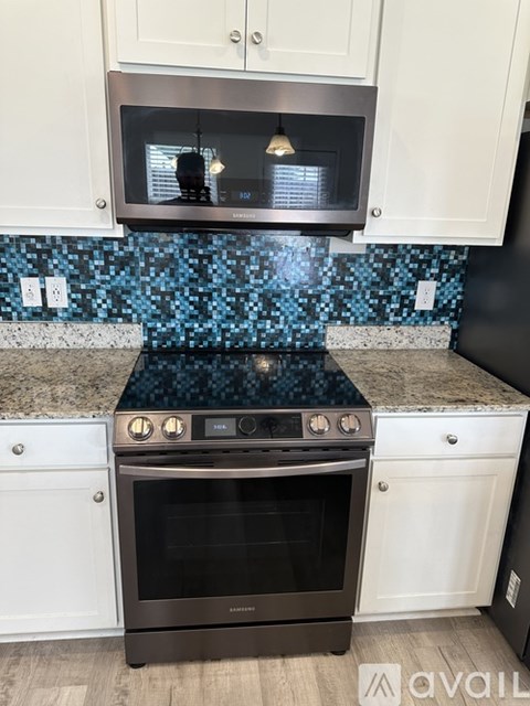 A kitchen with a black oven and a blue tile backsplash.