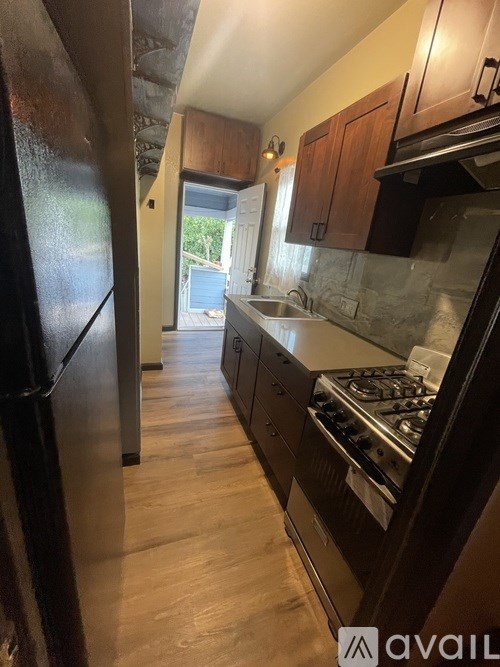 A kitchen with a black fridge and wooden cabinets.