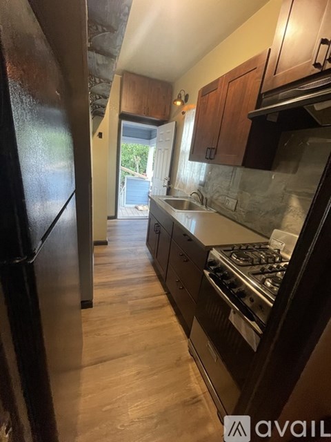 A kitchen with a black fridge and wooden cabinets.
