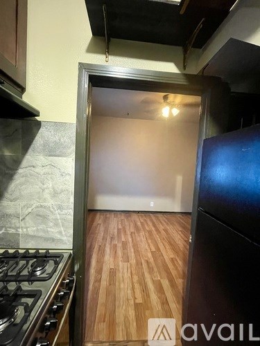 A kitchen with a stove and a wooden floor leading to a door.
