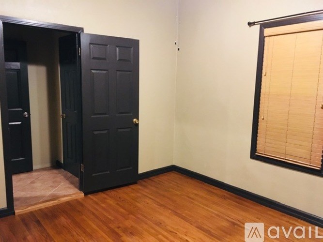 A room with a black door and a window with blinds.