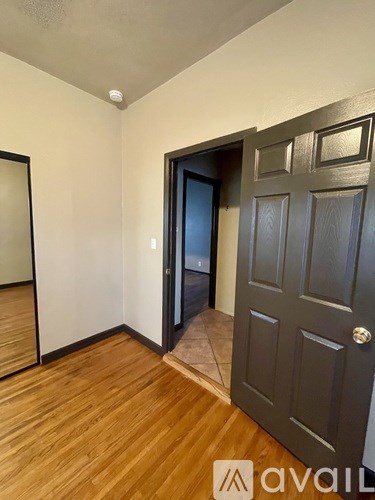 A room with a black door and a wooden floor.