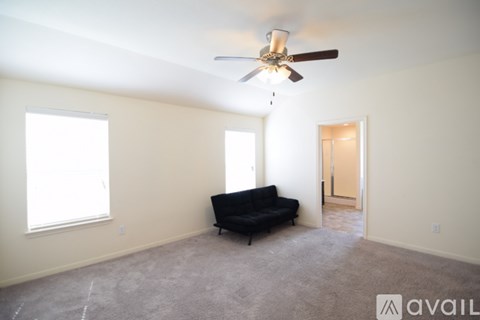 A living room with a black couch and a ceiling fan.