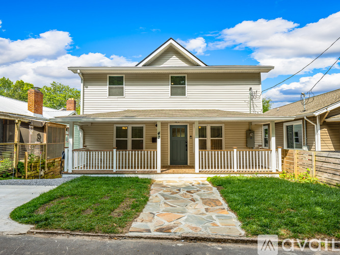 A two-story house with a front porch and a stone pathway leading to the front door.