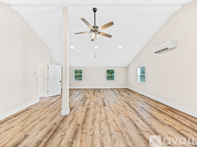 A spacious room with wooden flooring and a ceiling fan.