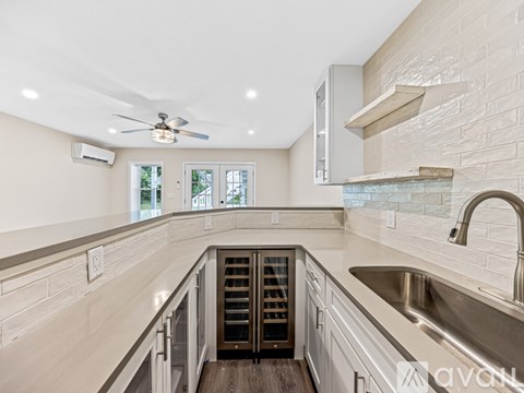 A modern kitchen with a stainless steel sink and a ceiling fan.