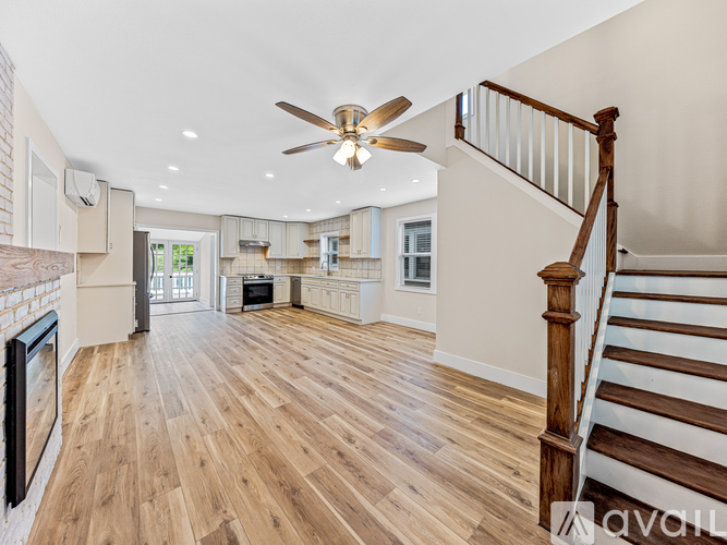 A spacious living room with wooden floors and a staircase.