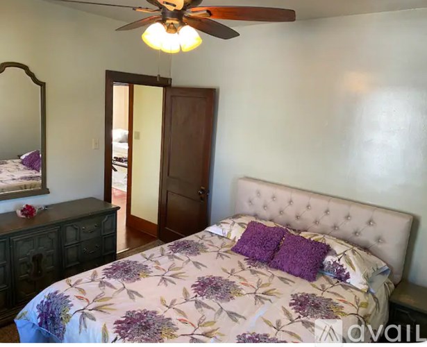 A bedroom with a floral bedspread and a ceiling fan.