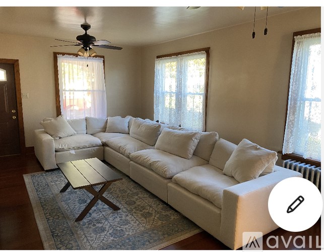 A white sectional sofa with a wooden coffee table in front of it.