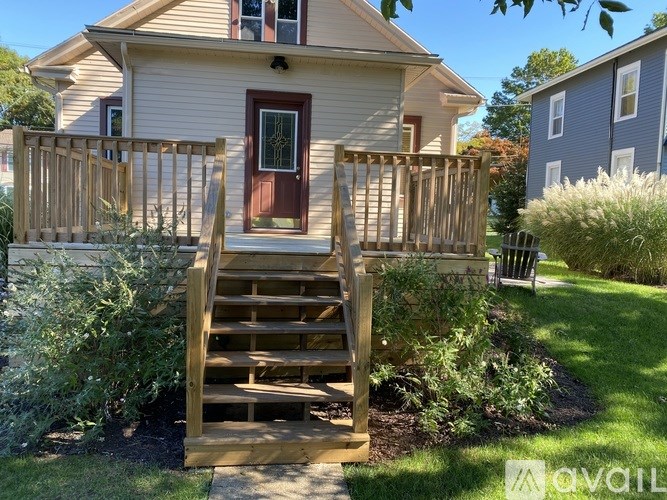 A house with a red door and a wooden staircase leading to the front door.