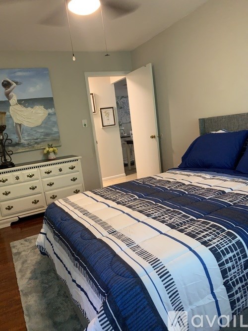 A bedroom with a bed, dresser, and painting.