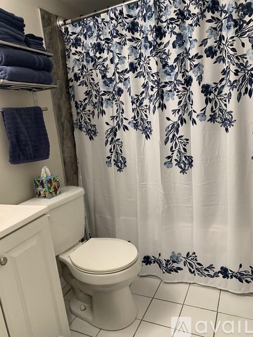 A white toilet with a floral shower curtain.