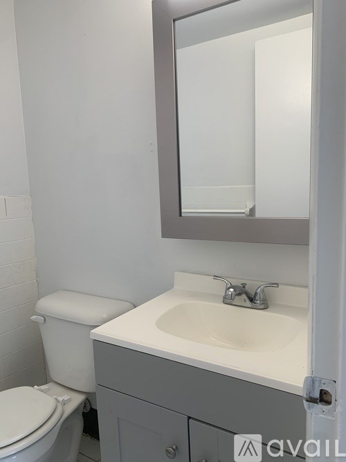 A bathroom with a toilet, sink and mirror.