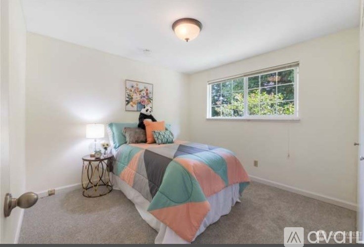 A bedroom with a bed, a nightstand, and a window.
