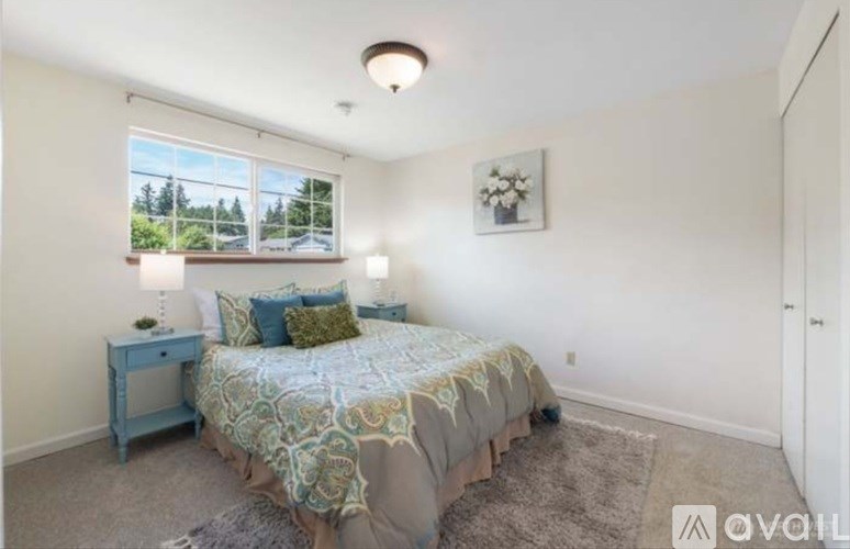 A bedroom with a bed, nightstand, and window.