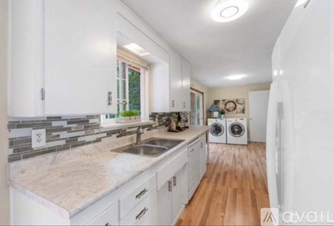 A kitchen with white cabinets and a marble countertop.