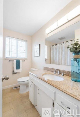 A bathroom with a toilet, sink, and mirror.