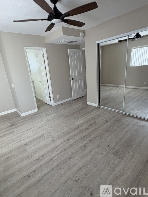 A room with a ceiling fan and wooden flooring.