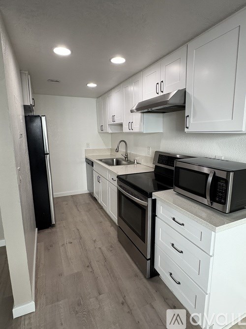 A kitchen with white cabinets and black appliances.