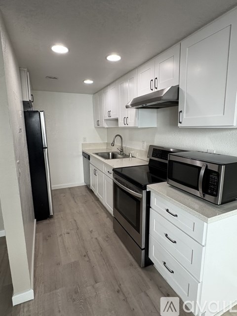 A kitchen with white cabinets and black appliances.