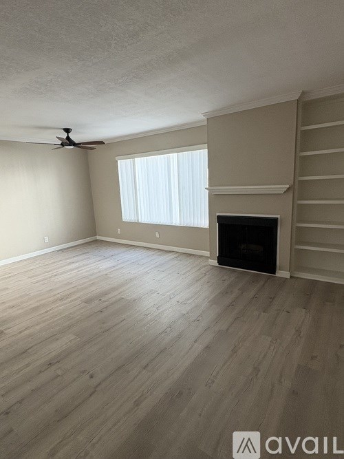 A living room with a fireplace and a ceiling fan.
