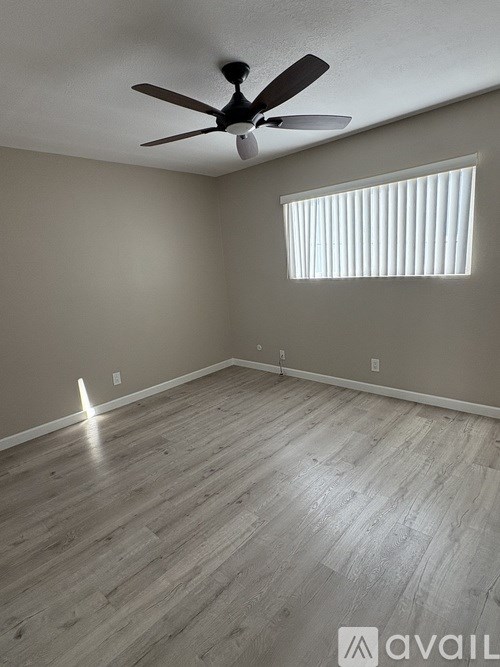 A room with a ceiling fan and a window with blinds.